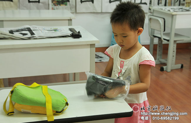 寫完書法自己收拾文房四寶，將毛氈疊放整齊塞入袋子中。